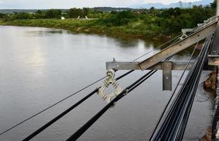 suspendre et conserver le stockage des câbles haute tension et des câbles à fibres optiques sur le côté des ponts fluviaux en béton dans les régions reculées de l'asie du sud-est, mise au point douce et sélective. photo