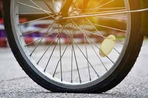 roue arrière du vélo qui est à plat et garée sur le trottoir à côté de la route. photo