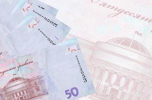 50 billets de hryvnias ukrainiens sont empilés sur fond de gros billets de banque semi-transparents. arrière-plan abstrait des affaires photo