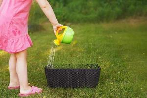 jolie petite fille arrosant des fleurs dans le jardin d'été photo