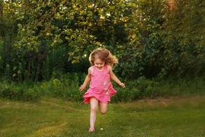 bébé heureux souriant. petite fille qui court au coucher du soleil en plein air photo