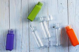 tube en plastique transparent sur un fond en bois bleu. bouteille multicolore vide en plastique pour agent de nettoyage détergent.