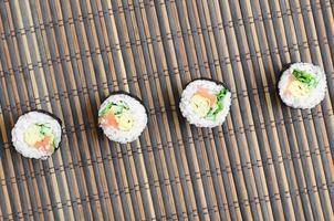 les rouleaux de sushi reposent sur un tapis de couture en paille de bambou. cuisine asiatique traditionnelle. vue de dessus. minimalisme à plat tourné avec espace de copie photo