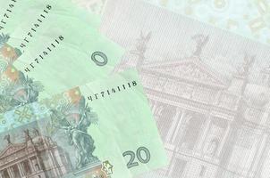 20 billets de hryvnias ukrainiens sont empilés sur fond de gros billets de banque semi-transparents. arrière-plan abstrait des affaires photo
