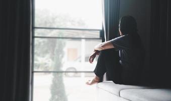 schizophrénie avec concept de dépression solitaire et triste en santé mentale. femme déprimée assise sur le canapé à la maison avec une pièce sombre se sentant misérable. les femmes sont déprimées, craintives et malheureuses.