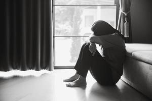 schizophrénie avec concept de dépression solitaire et triste en santé mentale. femme déprimée assise contre le sol à la maison avec une pièce sombre se sentant misérable. les femmes sont déprimées, craintives et malheureuses.