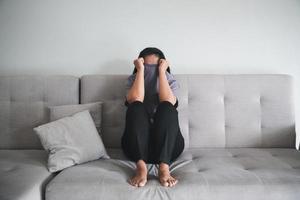 schizophrénie avec concept de dépression solitaire et triste en santé mentale. femme déprimée assise sur le canapé à la maison avec une pièce sombre se sentant misérable. les femmes sont déprimées, craintives et malheureuses. photo