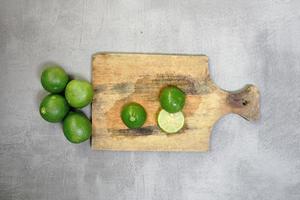 citron vert frais sur une planche à découper sur fond de béton photo