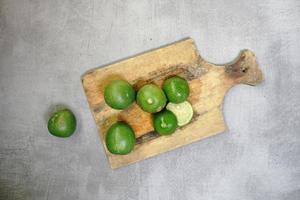 citron vert frais sur une planche à découper sur fond de béton photo