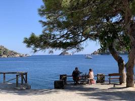 paysage d'été en turquie près de marmaris. vue sur la baie et les montagnes à travers les branches de pin. couple sur le banc. photo