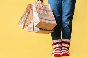 livraison de cadeaux de noël shopping sacs en papier kraft cadeaux et enfant en chaussettes tricotées fond jaune isolé photo