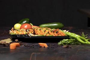 paneer tikka est un plat indien à base de morceaux de paneer avec sauce et légumes sur la table photo