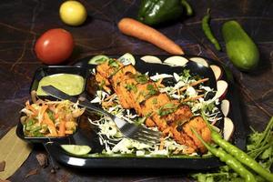 paneer tikka est un plat indien à base de morceaux de paneer avec sauce et légumes sur la table photo
