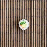le rouleau de sushi est posé sur un tapis de couture en paille de bambou. cuisine asiatique traditionnelle. vue de dessus. minimalisme à plat tourné avec espace de copie photo