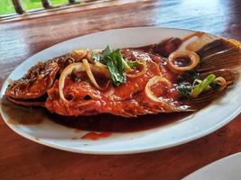 poisson gurame aigre-doux, une spécialité indonésienne sous forme de poisson gourami frit assaisonné de sauce aigre-douce rouge au goût légèrement épicé. photo