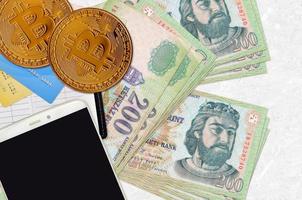 200 billets de forint hongrois et bitcoins dorés avec smartphone et cartes de crédit. concept d'investissement en crypto-monnaie. minage ou commerce de crypto photo
