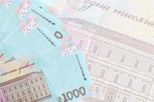 1000 billets de hryvnias ukrainiens sont empilés sur fond de gros billets semi-transparents. arrière-plan abstrait des affaires photo