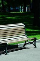 Banc en bois vide dans le parc d'été contre l'herbe verte photo