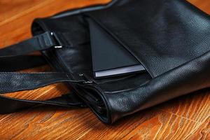 cahier noir sortant de la poche d'un gros plan de sac en cuir noir, macro fait à la main, matériaux naturels. photo