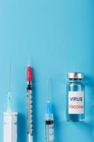 seringues et ampoule avec le vaccin contre le virus des maladies sur fond bleu.