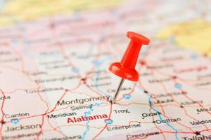 aiguille de bureau rouge sur une carte des états-unis, du sud de l'alabama et de la capitale montgomery. gros plan du sud de l'Alabama avec tack rouge photo