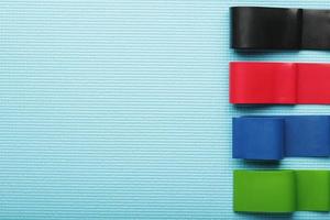 bandes élastiques de fitness de différentes couleurs et charges pour le sport sur fond bleu. photo