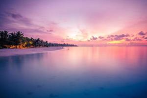 coucher de soleil du soir, ciel du lever du soleil. plage pittoresque avec reflet de la mer sur des nuages colorés à l'horizon. paysage tropical, fond de plage idyllique au coucher du soleil photo