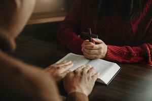 main de femme avec croix. concept d'espoir, de foi, de christianisme, de religion, d'église et de prière à dieu. sur la table photo