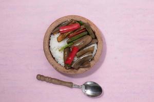 bol de riz et aubergines frites dans une assiette sur fond rose. photo