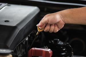 main d'homme tirant la jauge d'huile pour vérifier le niveau de lubrifiant d'huile moteur dans le moteur, concept de service d'entretien de voiture. photo