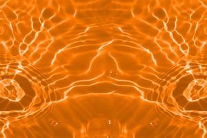 défocalisation floue transparente couleur orange clair texture de surface de l'eau calme avec des éclaboussures et des bulles. fond de nature abstraite à la mode. vagues d'eau au soleil avec espace de copie. eau orange qui brille photo