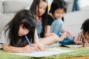 groupe d'enfants dessinant en classe, jeunes garçons et filles multiethniques heureux et drôles étudient et jouent à la peinture sur papier à l'école primaire. enfants dessinant et peignant au concept d'école. photo