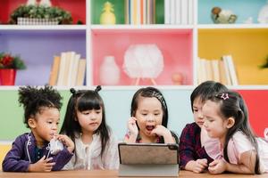 groupe d'enfants utilisant une tablette en classe, jeunes garçons et filles multiethniques heureux d'utiliser la technologie pour étudier et jouer à des jeux à l'école primaire. les enfants utilisent la technologie pour le concept d'éducation. photo