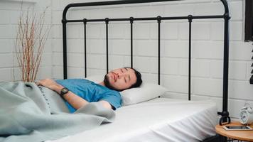 jeune homme asiatique se réveille le matin, homme s'étirant après s'être réveillé sur le lit dans la chambre à la maison. beaux hommes sieste, somnolent se détendre dans le concept de maison moderne. photo