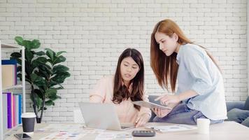 attrayantes femmes d'affaires asiatiques créatives intelligentes dans des vêtements décontractés intelligents travaillant sur un ordinateur portable tout en étant assis sur le bureau sur le bureau. les femmes travaillent au concept de bureau. photo