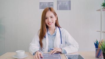 femme médecin asiatique confiante assise au bureau et souriant à la caméra, concept de soins de santé et de prévention dans un cabinet médical. photo