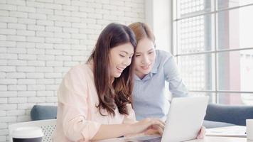 séduisantes femmes d'affaires asiatiques créatives intelligentes en vêtements décontractés intelligents travaillant sur un ordinateur portable tout en étant assises sur le bureau sur le bureau. les femmes de style de vie travaillent au concept de bureau. photo