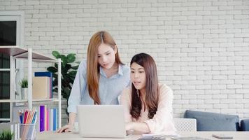 séduisantes femmes d'affaires asiatiques créatives intelligentes en vêtements décontractés intelligents travaillant sur un ordinateur portable tout en étant assises sur le bureau sur le bureau. les femmes de style de vie travaillent au concept de bureau. photo