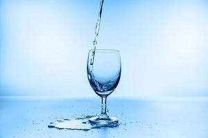 collection d'éclaboussures d'eau dans un verre à vin isolé sur fond bleu photo