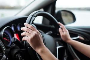 les mains des femmes sur le volant, à l'intérieur de la voiture. photo