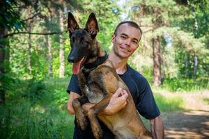 le jeune hipster caucasien passe du temps avec son chien dans le parc par une journée d'été ensoleillée. le concept d'un animal de compagnie en tant que membre de la famille photo