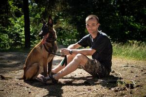 le jeune hipster caucasien passe du temps avec son chien dans le parc par une journée d'été ensoleillée. le concept d'un animal de compagnie en tant que membre de la famille photo