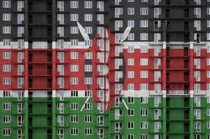 drapeau du kenya représenté dans des couleurs de peinture sur un immeuble résidentiel à plusieurs étages en construction. bannière texturée sur fond de mur de brique photo