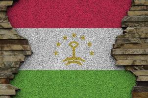 drapeau du tadjikistan représenté dans des couleurs de peinture sur un vieux mur de pierre agrandi. bannière texturée sur fond de paroi rocheuse photo