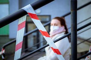 photo d'une fille dans un masque. assis dans la rue avec des bandes d'avertissement de danger.