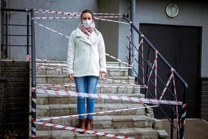 photo d'une fille dans un masque. debout dans la rue avec des bandes d'avertissement de danger.