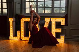 femme en robe rouge faisant la lettre v devant des lettres d'amour photo