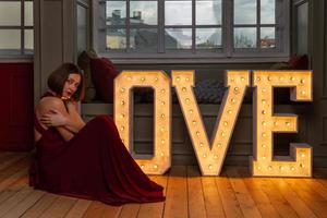 femme aux bras croisés en robe rouge faisant la lettre l devant des lettres d'amour photo