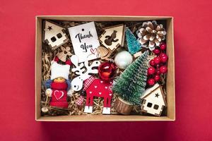 paquet de soins faits à la main, coffret cadeau saisonnier avec jouets, décor de noël sur table rouge panier écologique personnalisé pour la famille, les amis, la fille pour le 24 décembre, noël, le jour de l'an à plat photo