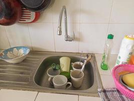 vaisselle et verres sales dans l'évier qui n'ont pas été lavés. des tas de vaisselle sale et des verres pas lavés, la vraie vie à la fin de l'année photo